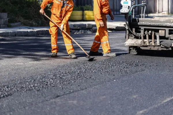 Crew raking asphalt during a managed and inspected road resurfacing project